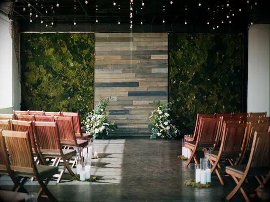 wedding ceremony backdrop with moss wall and small flower arrangements on the floor