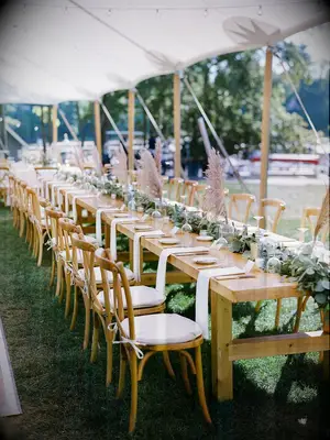 long wooden reception table with greenery runner and pampas grass
