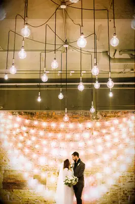 inexpensive wedding backdrop idea with bistro lights against a brick wall 