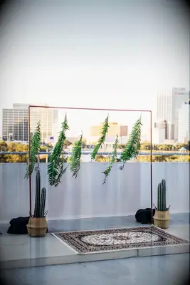 boho wedding ceremony backdrop with greenery leaves hanging from copper square frame