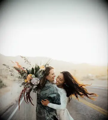 Couple hugging in the desert and holding bouquet