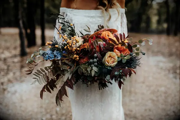 unique fall wedding bouquet with orange roses, greenery and red fall foliage