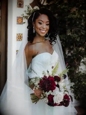 Bride wearing veil and holding burgundy bouquet