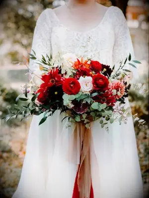 Bride holding bright red bouquet with ribbon