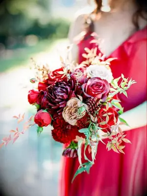 Bridesmaid in red dress holding red bouquet