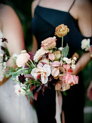 Bridesmaid in black dress holding wedding bouquet
