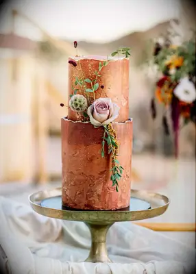 A stunning copper-toned cake in two tiers, complemented by pale pink roses.
