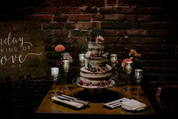 A gorgeous three-tiered naked wedding cake, complemented by cut fresh red figs.
