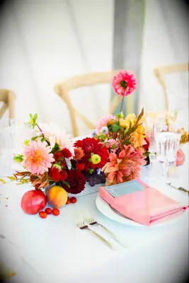 A cheerful table arrangement of red and pink dahlias.