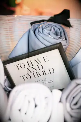 A basket of soft blanket wedding favors in neutral tones.