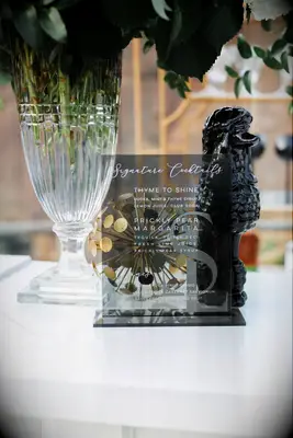 A glass cocktail menu sat beside a floral arrangement.