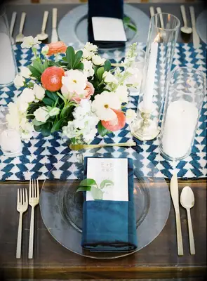 A beautiful place setting in jewel-toned blue with a lovely floral arrangement in coral and white.