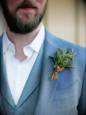 A groom shows off this delightful understated greenery boutonniere.