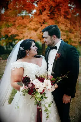 The happy couple gaze into each others eyes before a background of warm, autumnal trees.