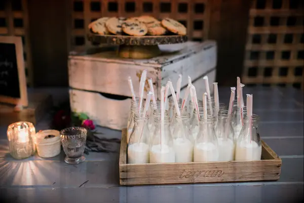 wedding dessert table with tray of chocolate chip cookies and milk in individual glass bottles with straws
