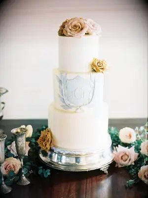 three-tier white fondant wedding cake with blue monogram and rose topper