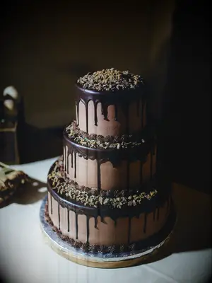 chocolate ganache wedding cake with drip icing and chopped nuts