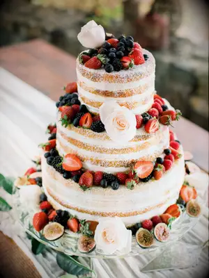 naked wedding cake with fresh berries and powdered sugar