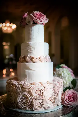 four tier wedding cake with piped rosettes and blush roses