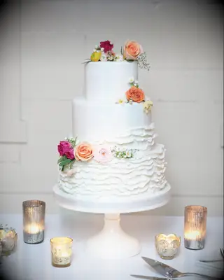 three tier fondant wedding cake with ruffles and colorful flowers