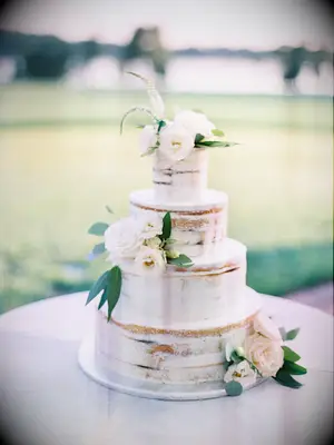 four-tier semi naked wedding cake with white flowers and greenery