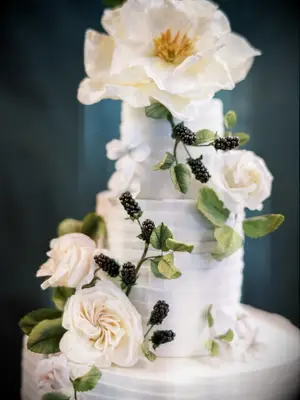 close-up of luxury wedding cake with sculpted sugar roses, berries and greenery 