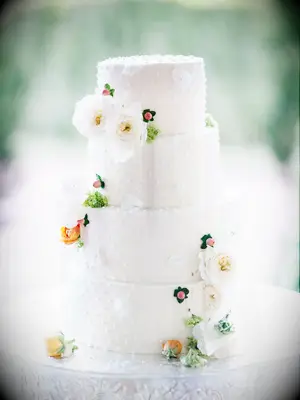 white wedding cake with swiss dot decoration and fresh flowers