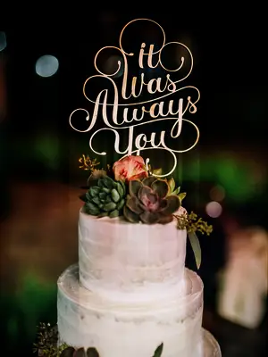 gold laser-cut wedding cake topper with the quote 