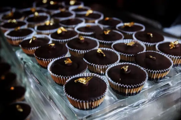 Tray of peanut butter cups topped with gold leaf. 