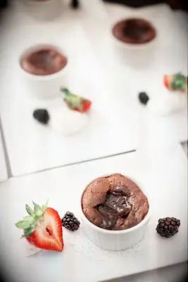 Delicious servings of chocolate lava cakes plated with selections of fresh fruit. 