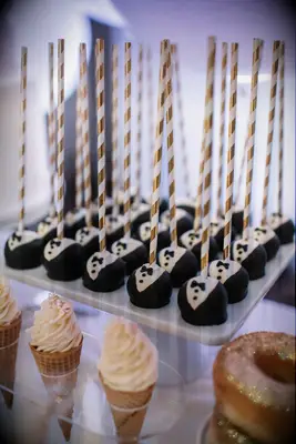 Tray of cake pops decorated to look like tuxedos. 