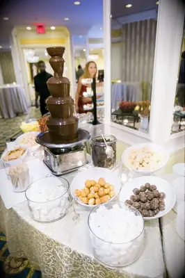 Chocolate fondue fountain surrounded by dessert items for dipping. 