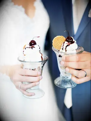 Newlyweds hold delicious individual ice-cream sundaes. 