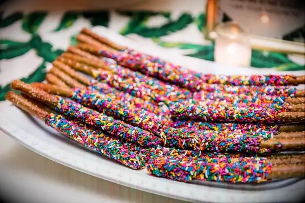 Pretzel sticks dipped in chocolate and covered in sprinkles. 