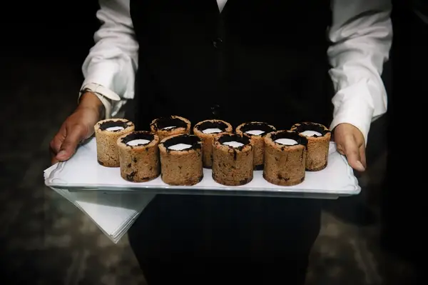 Server holds a tray of milk and cookie shooters. 