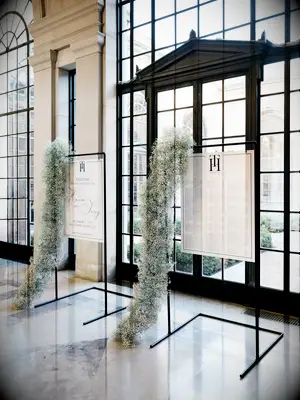 modern wedding seating chart display with white signs hanging from minimalist black pipe stands and decorated with baby