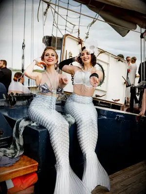 Entertainers dressed as mermaids at nautical summer wedding on boat