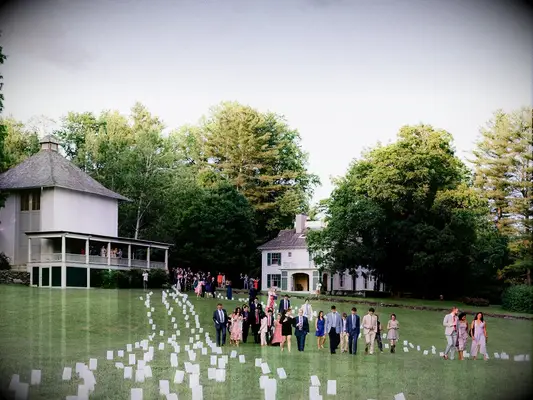 Wedding guests walking through paper lantern pathway at outdoor summer wedding