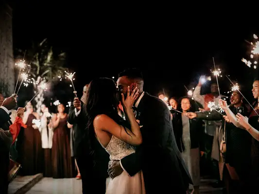 Bride and groom kissing under sparkler exit at summer wedding reception