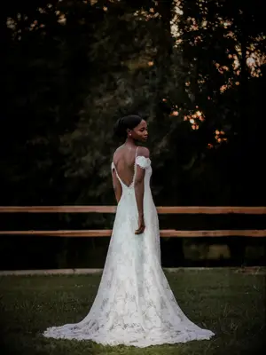 Bride wearing cold-shoulder wedding dress with plunging back at outdoor summer wedding ceremony