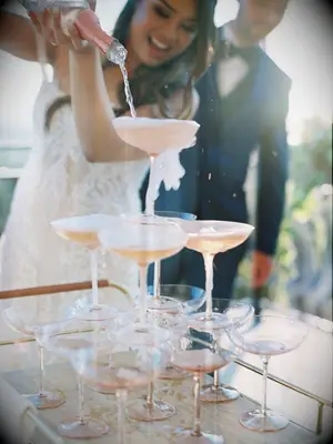 Bride pouring champagne over glasses arranged in a tower