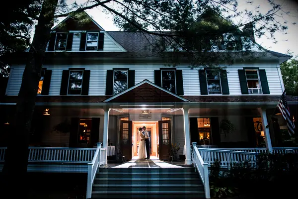 Couple posing at the doorway of the wedding venue at dusk