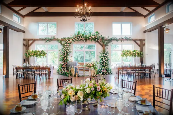 Inside charming wedding reception space with wooden beams and hanging foliage