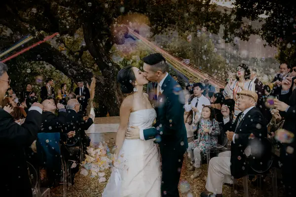 Newlyweds share a kiss at their whimsical outdoor recessional. 
