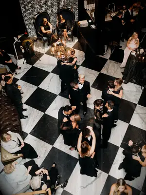 aerial view of wedding guests dancing on top of black and white checkerboard tile dance floor