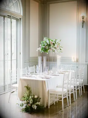classic wedding reception table with tall centerpieces and white chiavari chairs