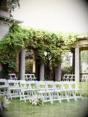 ceremony chairs lined up at garden wedding venue with grecian-style pillars covered in ivy