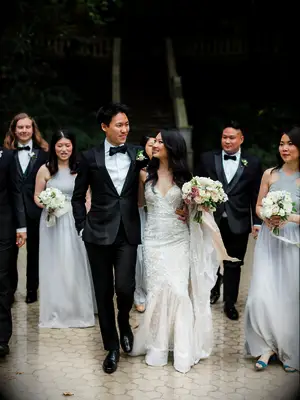 bride and groom wearing formal wedding attire walk with bridesmaids and groomsmen behind them