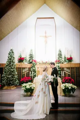 Bride and groom having a photo shoot in a church with poinsettias.