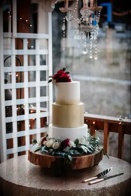 Gold and ivory cake with red and white roses around it.